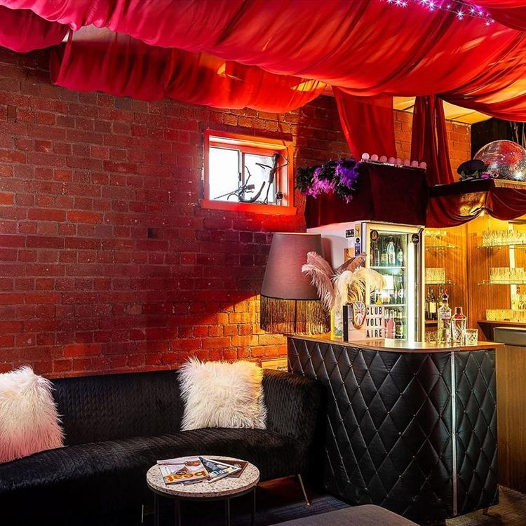 The bar and lounge, with red drapes, a velvet couch and a stocked bar